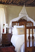 Bürgerliches Schlafzimmer mit antikem, imposantem Holzbett mit Baldachin, Nachtkästchen und alter Holzdecke