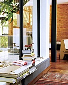 Bücherstapel auf der Fensterbank; im Hintergrund eine Backsteinwand