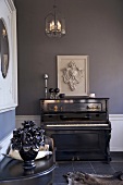 Schwarzes, antikes Klavier vor blauer Wand mit hängendem Löwenrelief