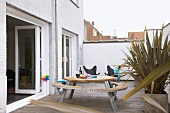 Round table with integrated benches and butterfly chairs on wooden terrace