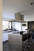 Modern kitchen with stainless steel island counter and black swivel stools