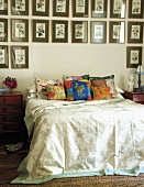 Double bed with colourful scatter cushions below large collection of pictures