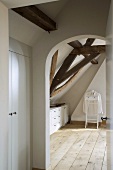 View through rounded archway of valet stand under sloping ceiling with rustic wooden beams