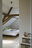 Dach-Schlafzimmer mit ausladendem Doppelbett und rustikalen Holzbalken darüber