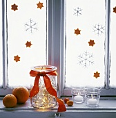 Wintry window decoration of candles, fairy lights, oranges