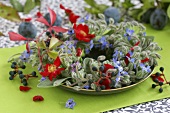 Wreath of borage, roses, vine leaves and plums