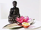 Half passion fruit & water lily in front of Buddha statuette