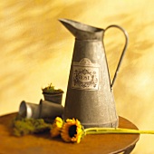 Metal jug with sunflowers in foreground