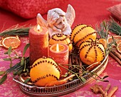 Mit Gewürznelken gespickte Orangen, Kerzen und ein Engel