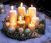 Candles and Christmas baubles on tray in snow (evening)