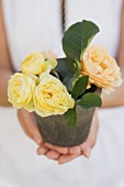 A woman holding a pot of yellow roses