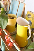 A yellow jug next to a yellow flowerpot