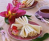 Folded napkin and pieces of cake on plate, lily
