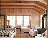 Offene Dachbalkenkonstruktion im Schlafzimmer eines Holzhauses mit Kamin und gemütliche Fensterbank