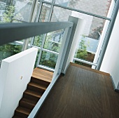 Dunkle Holztreppe vor Glasfensterfront mit Blick in den Innenhof