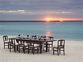Ein gedeckter Tisch am Strand bei Sonnenuntergang