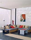 Ein modernes Wohnzimmer mit Rattanmöbel und bunte Sitzpolster vor Panoramafenster