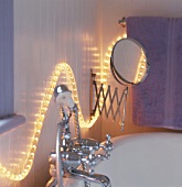 Eine leuchtende Lichterkette über Badewannenarmaturen und Kosmetikspiegel