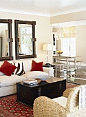 Offener Wohn- und Essbereich mit weißer Couch und Truhe als Tisch unter Wandspiegel