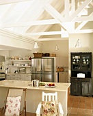 Küche mit Kochinsel und Edelstahl-Kühlschrank unter ausgebautem Dachstuhl