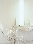 A transparent plastic chair in front of a lamp