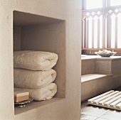 Gerollte Handtücher und ein Seifenblock in einer gemauerten Nische