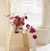 Verschiedene Blumen als Deko in Vasen auf einem Hocker