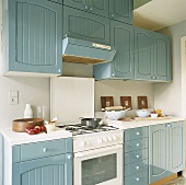 Eine Landhausküche mit blau-grauen Schrankfronten und einem Gasherd