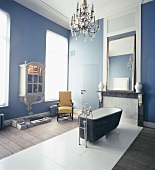 Ein barockes Badezimmer mit hohen blauen Wänden und Kronleuchter über freistehende Badewanne
