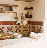 Eine rustikale Spüle mit gemusterten Wandfliesen und dreckigem Geschirr