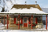 Snow-covered wooden house with roofed veranda decorated for Christmas
