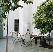 Butterfly chairs in stone-flagged courtyard with opening left for tree