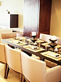 Place setting, place mats and decorations on exotic-wood table with replica designer armchairs