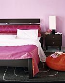 Schlafzimmer mit pastellfarbener Wand und mit farbchangierendem Bettüberwurf; ein Goldmuster veredelt die Kissen