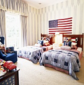 Zwei Einzelbetten mit identischen Tagesbettdecken vor der amerikanischen Flagge an der Wand