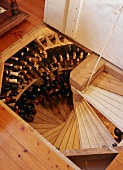 Blick durch offene Bodenlucke auf Weldeltreppe und Weinflaschen entlang der Wand