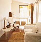 weiße Couch und Sessel vor Fensterfront und Blick durch offene Terrassentür