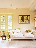 weiße 2-Sitzer Couch und mintgrüne Wolldecke unter Wandbild mit afrikanischem Motiv