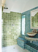 Grün-blau gefliestes Badezimmer mit offene Dusche und Waschtisch unter Wandspiegel