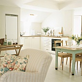 Kleine Küchenzeile unter Dachschrägen und eine Wandnische mit Kühlschrank im offenen Wohn- und Essraum