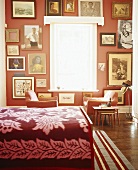 Eine dekorative Bildersammlung an der roten Wand eines Schlafzimmers