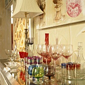 Gläser und Karaffen in verschiedenen Farben und Stilen auf einer Glaskommode
