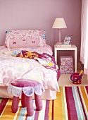 Child's bedroom in pink with bed, rug and stool