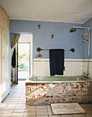 Badewanne in nicht verputzter Backsteinmauer und Holzsteg