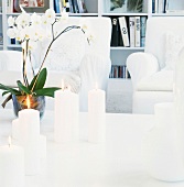 Brennende weiße Kerzen und weiße Orchidee auf Couchtisch