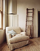 Armchair and ladder leaning against wall