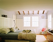 Helles, freundliches Schlafzimmer mit drei Schiebefenstern und filigranen Holzbalken an der Decke