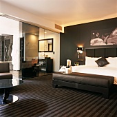 Luxuriöses, schwarz-weisses Schlafzimmer mit gepolsteter Ledersitzbank und Badezimmer en suite
