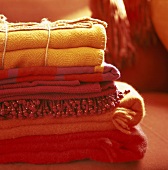 Folded woollen blankets in shades of orange and red