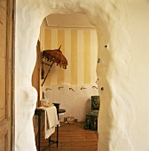 Blick durch einen rustikalen Durchgang in ein dekoriertes Badezimmer mit Streifenmuster